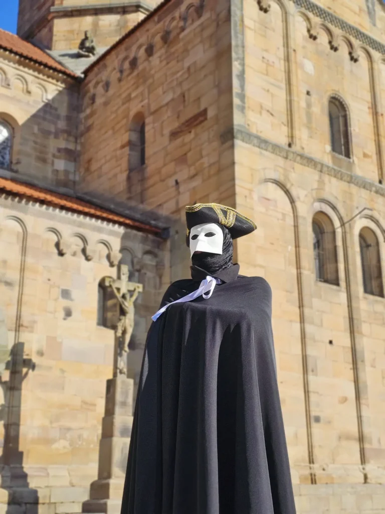 Vue de l’église romane de Rosheim avec personnage du carnaval vénitien